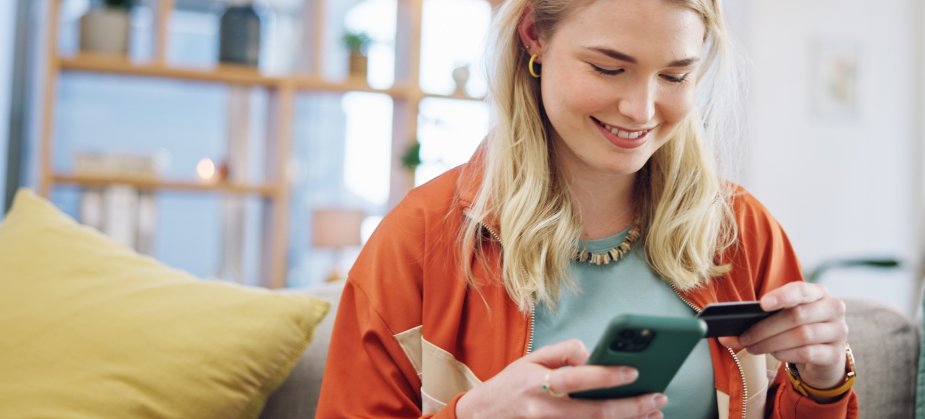 Woman smiling holding card and looking at phone
