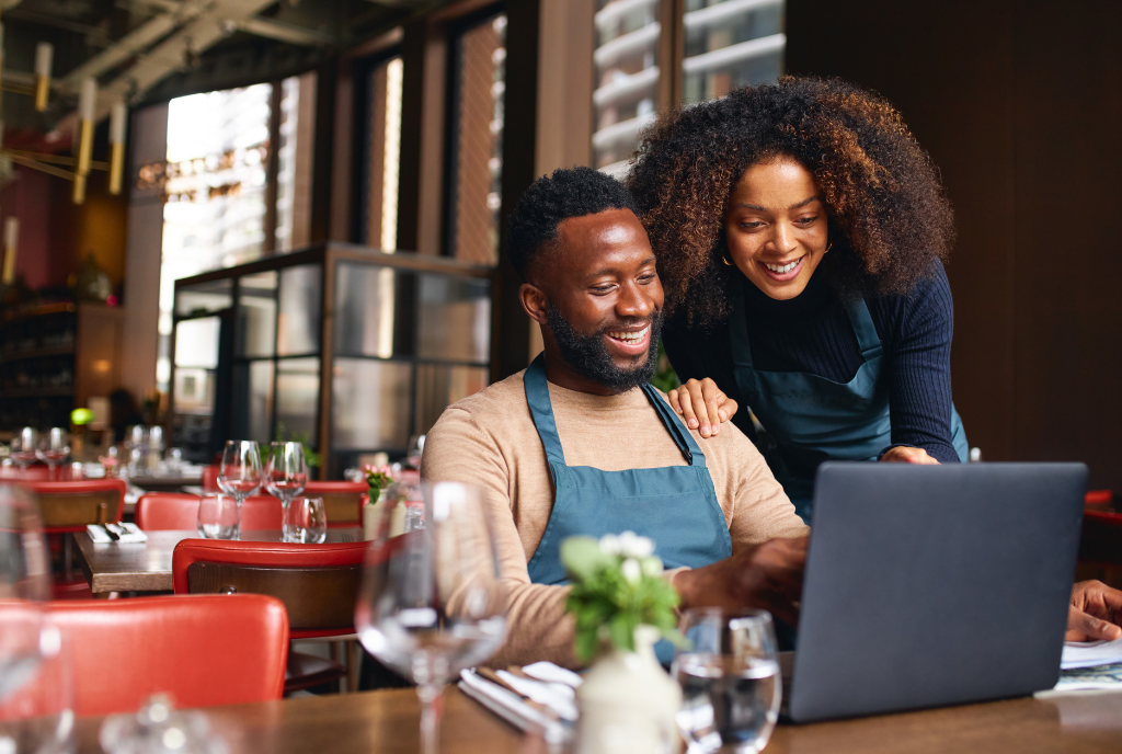 Man and woman looking at a laptop in a restaurant