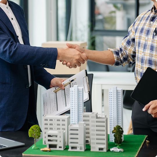 Business people shaking hands over a model building