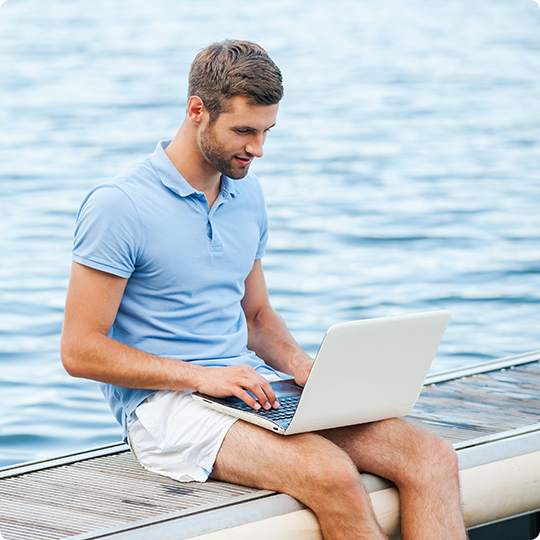 man on laptop near water
