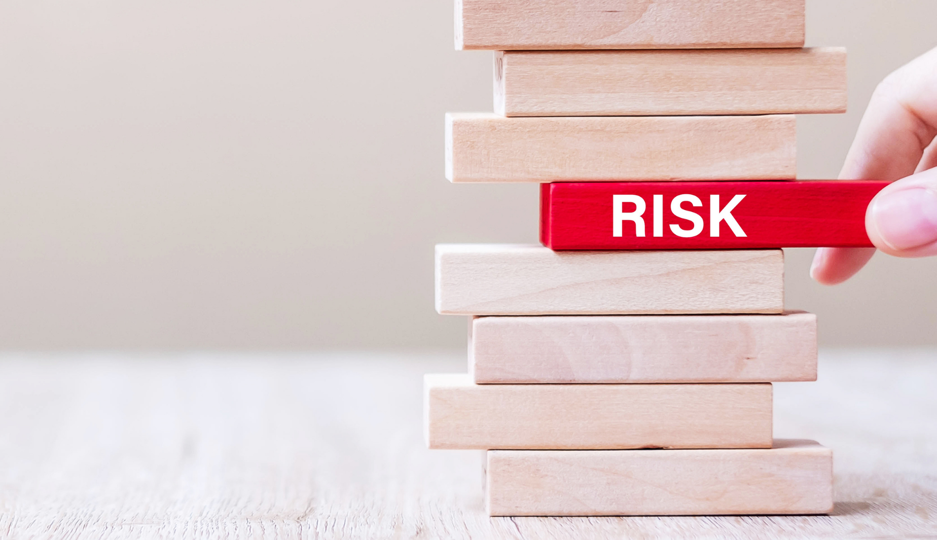 stack of block with someone pulling out the block that says risk
