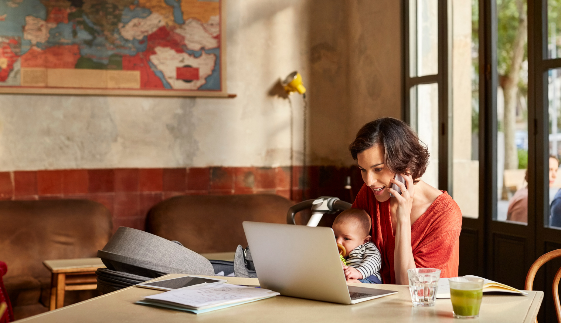 mother on phone with baby on lap looking at laptop