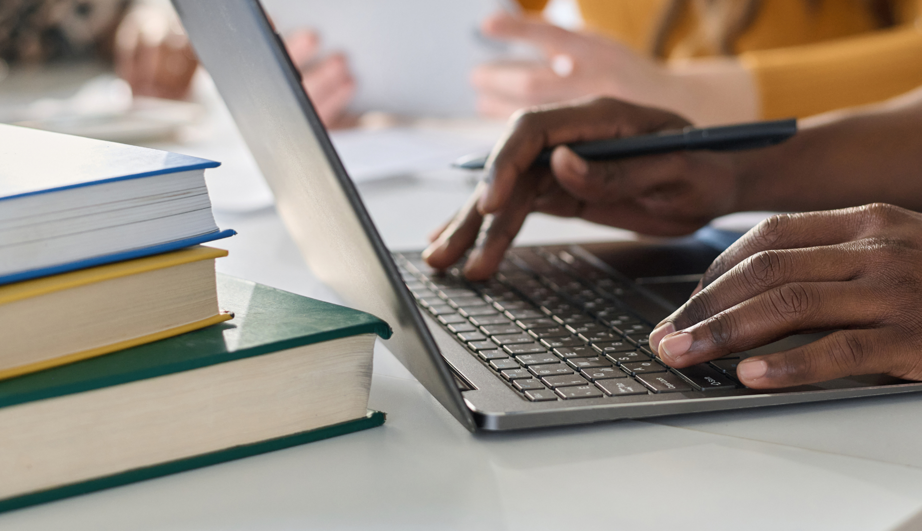 Person on laptop with books on desk