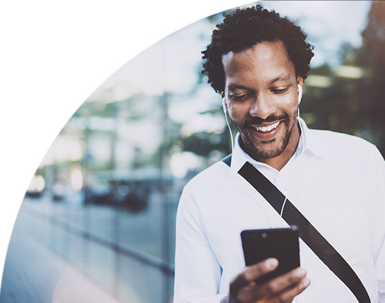 man staring at phone smiling with headphones